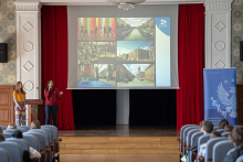 Aula wykładowa, w głębi dwie dziewczyny przy mównicy, za nimi ekran, na którym widać zdjęcia z atrakcjami turystycznymi Kopenhagi