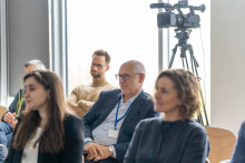 Grupa ludzi siedzących na krzesłach w sali konferencyjnej. Jest wśród nich starszy mężczyzna w granatowym garniturze - prof. Rafał Krenke, rektor WUM. W tle widoczna jest kamera na statywie.