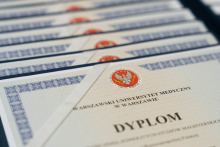 Zdjęcie przedstawia dyplomy ukończenia studiów magisterskich Warszawskiego Uniwersytetu Medycznego, starannie ułożone w rzędach.
