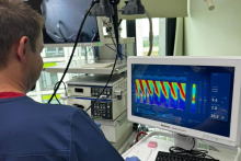 W szpitalnym pomieszczeniu lekarz w niebieskim uniformie, patrząca na monitor komputera.