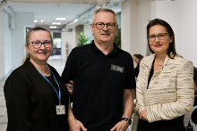 Trzy osoby: dwie kobiety, jedna po lewej, druga po prawej, a w środku mężczyzna. Są nieformalnie ubrani. Lekko się uśmiechają. Wszyscy noszą okulary.