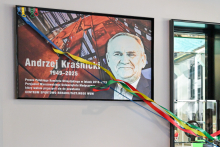 Tablica pamiątkowa z portretem Andrzeja Kraśnickiego (1949–2025) i tekstem o jego roli w Polskim Komitecie Olimpijskim oraz wsparciu dla WUM. Tablica ozdobiona kolorowymi wstążkami: niebieską, żółtą, czerwoną i zieloną. Obok znajduje się przeszklona witryna.