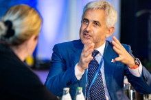 Two people, on the left a woman with her back to the camera, on the right a man—Dr. Wojciech Feleszko. The man is explaining something, both hands raised.