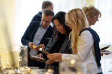 Grupa osób oglądająca przedmioty artystyczne wystawiona na wystawie na stole