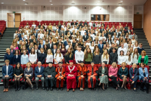 Grupa młodych osób - studentów oraz dziekan, prodziekanki, prorektor i inne osoby - ubrane formalnie, pozują do zdjęcia. Osoby w pierwszym rzędzie - władze uczelni i wydziału oraz zaproszeni goście siedzą, pozostali stoją.