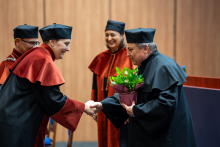 Dziekan i prodziekanki wręczają kwiaty dr. Białkowi. Wszyscy się uśmiechają.