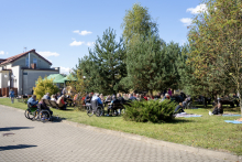 People in wheelchairs and on benches in a garden