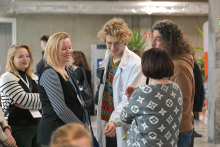 Six people standing in a room and talking in a group.