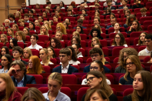 Sala z czerwonymi fotelami, na których siedzą uczestnicy inauguracji.