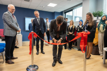 Dziekan przecinający wstęgę. Za nim i obok niego stoją pozostali uczestnicy wydarzenia.