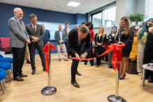 Prodziekan przecinający wstęgę. Za nim i obok niego stoją pozostali uczestnicy wydarzenia.