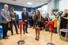 Kierowniczka dziekanatu przecinająca wstęgę. Za nią i obok niej stoją pozostali uczestnicy wydarzenia.