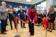 Kierowniczka Działu Wsparcia Projektu dziekanatu przecinająca wstęgę. Za nią i obok niej stoją pozostali uczestnicy wydarzenia.