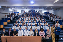 Studenci w białych fartuchach siedzą w auli. 