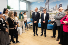 Kilkanaście osób - uczestników otwarcia - stoi w półkolu. Uśmiechają się do siebie i rozmawiają.