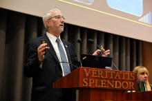 Starszy mężczyzna przemawia na podium. Gestykuluje.