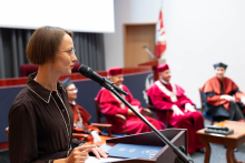 Konsultantka wojewódzka w dziedzinie diagnostyki laboratoryjnej województwa mazowieckiego przemawia zza mównicy. W tle widać władze dziekańskie i prorektora.