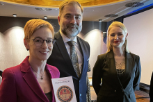 Trzy osoby: dwie kobiety i mężczyzna pozują do zdjęcia. Uśmiechają się. Jedna z kobiet ma dłoniach książkę poświęconą prof. Kossakowskiemu.