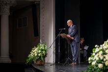The rector stands on stage and speaks into the microphone.
