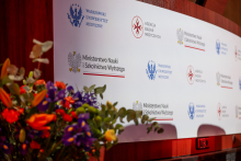 A wall with the logos of the Medical University of Warsaw and the Ministry of Science. Next to the wall stands a large bouquet of flowers.