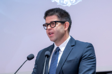 Łukasz Jankowski stoi przy mównicy i przemawia podczas konferencji. 