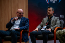 Dwóch mężczyzn w auli podczas panelu dyskusyjnego. 