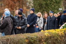 Grupa osób, w kurtach, stoi na dworze.