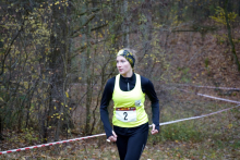 Młoda kobieta ubrana na sportowo, z numerem 2 na koszulce biegnie po wytyczonej ścieżce w parku.