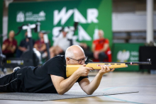 Rektor WUM, ubrany na sportowo, strzela w pozycji leżącej z laserowej broni.