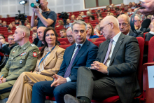 Grupa uczestników konferencji. Siedzą i rozmawiają, niektórzy patrzą przed siebie. 