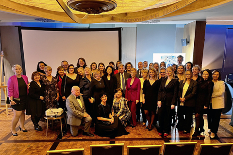 Grupa elegancko ubranych osób pozuje do zdjęcia w dużej sali. Są to uczestnicy jubileuszu 75-lecia Kliniki Chirurgii Dziecięcej.